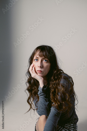 Portrait of a young woman with long wavy hair and blue eyes on a cyclorama. Feminine photo shoot