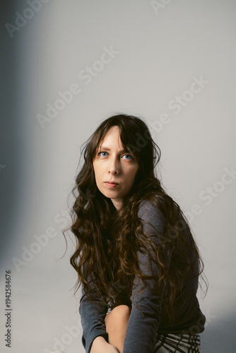 Portrait of a young woman with long wavy hair and blue eyes on a cyclorama. Feminine photo shoot