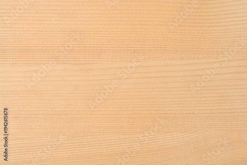 Full frame texture of a smooth light brown wooden surface with natural horizontal grain patterns and a small dark knot
