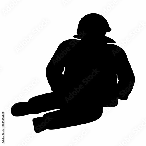 Silhouette of a soldier sitting on the ground wearing a helmet