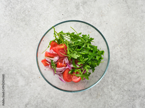 Fresh salad ingredients are mixed together in a glass bowl for a healthy meal preparation