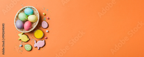 Φωτογραφία Colorful easter cookies in basket with Multi colors Easter eggs on colored background