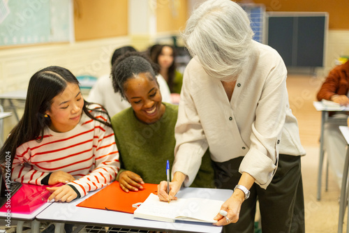 Quadro su tela Teacher helping high school students during lesson in class