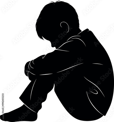 Silhouette of a lonely depressed young boy sitting on floor with head down on knees representing childhood depression and sadness