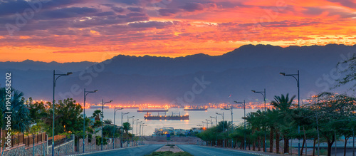 Fotografie Sunset above the gulf of Aqaba with cargo ships, marine port and light streets