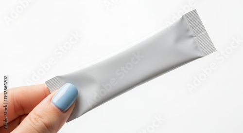 Hand holding a white blank stick sachet package on a white background, ideal for product mockups and branding presentations.