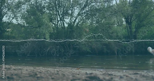 Fototapeta samoprzylepna Flowing shallow river and treeline framing sandy riverbank, with dotted waveform and dog tail