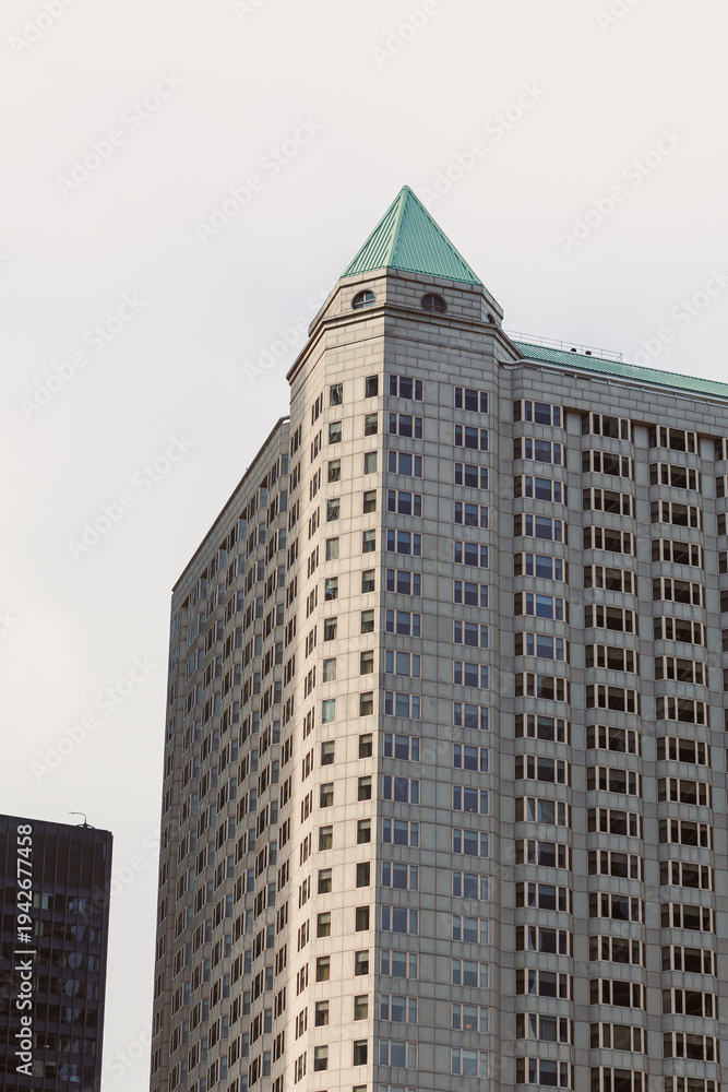 Fototapeta premium Tall building with a green roof in an urban area showing modern architecture