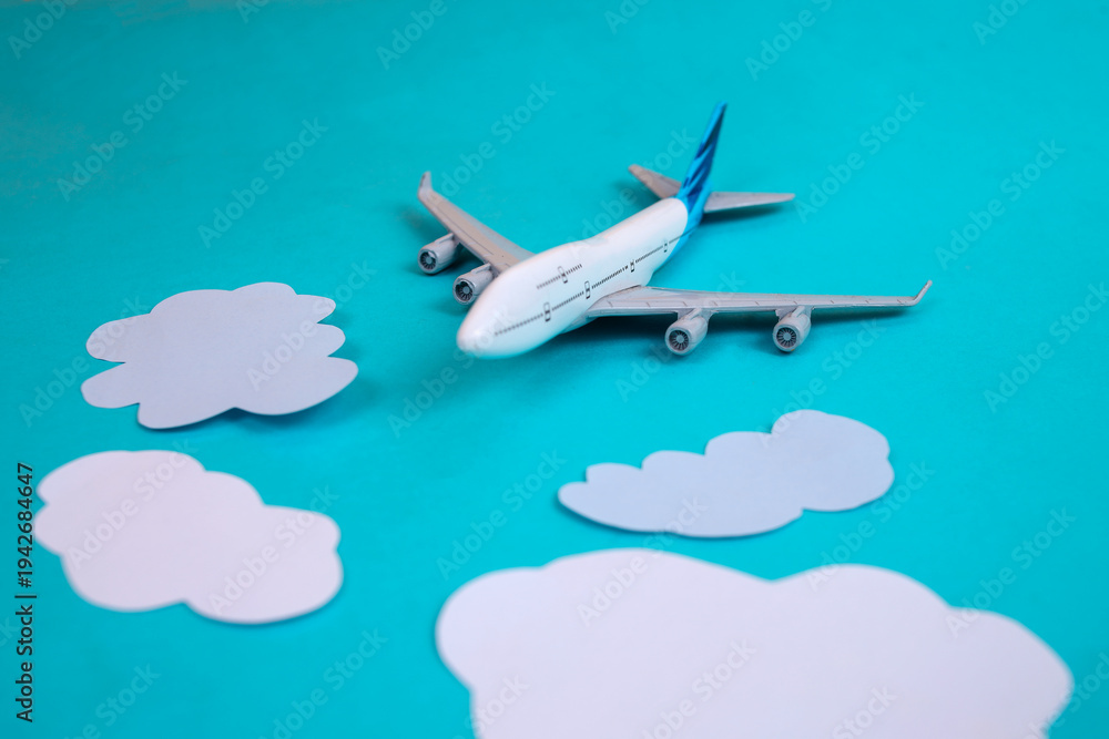 Naklejka premium Toy Airplane Soaring Through White Clouds On Blue Background