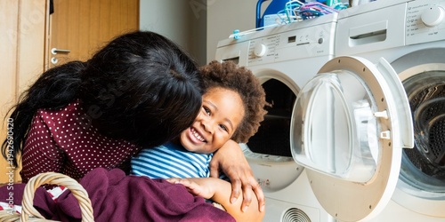 Tableau sur toile A woman hugs a smiling child in front of a washing machine