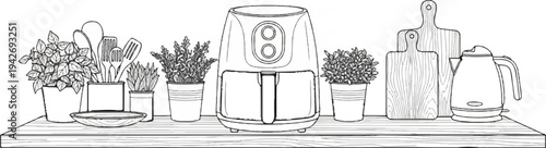 A kitchen counter display with an air fryer, plants, utensils, cutting boards, and kettle