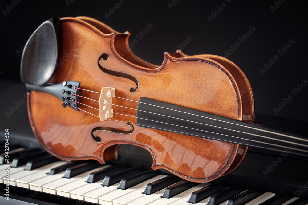 Fototapeta premium Violin on top of piano keys with black background