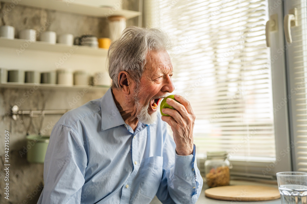 Obraz premium Senior adult man holding green apple in kitchen