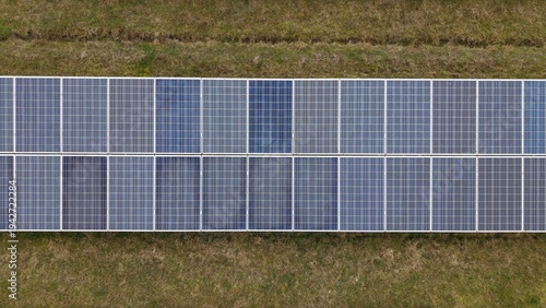 Aerial view of solar panels gleaming softly amidst bordering green fields, a symphony of modern technology harmonizing with nature's tranquility, Huntingdon, Cambridgeshire, United Kingdom.