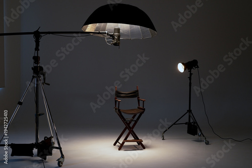 Professional photo studio setup with a director's chair, studio lights, softbox, and a flash on a boom.