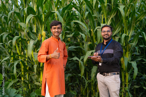 Εκτύπωση καμβά young indian adviser and farmer standing together at green corn field