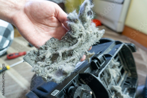 A dirty vacuum cleaner filter clogged with dust and hair. Concept of cleaning and allergies.