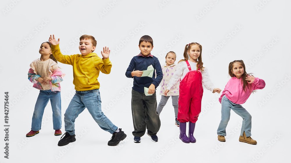 Obraz premium Group of children dancing wearing colorful mid season kids fashion outfits in studio. Concept of kids fashion campaign, retail apparel promotion and playful lifestyle marketing.