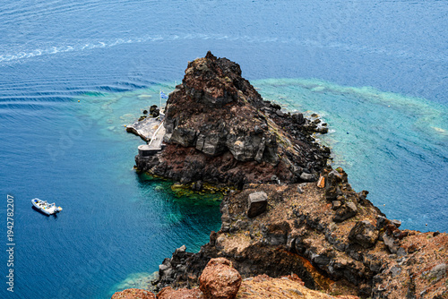 santorini - promontorio nel mare con barca e sfumature azzurre
