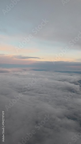 Aerial View of Fluffy White Clouds Moving Past Airplane Window at High Altitude