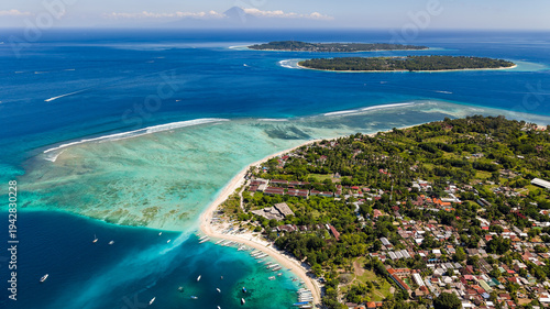 High angle view over lush coastal village, blue ocean, boats and distant mountain peaks