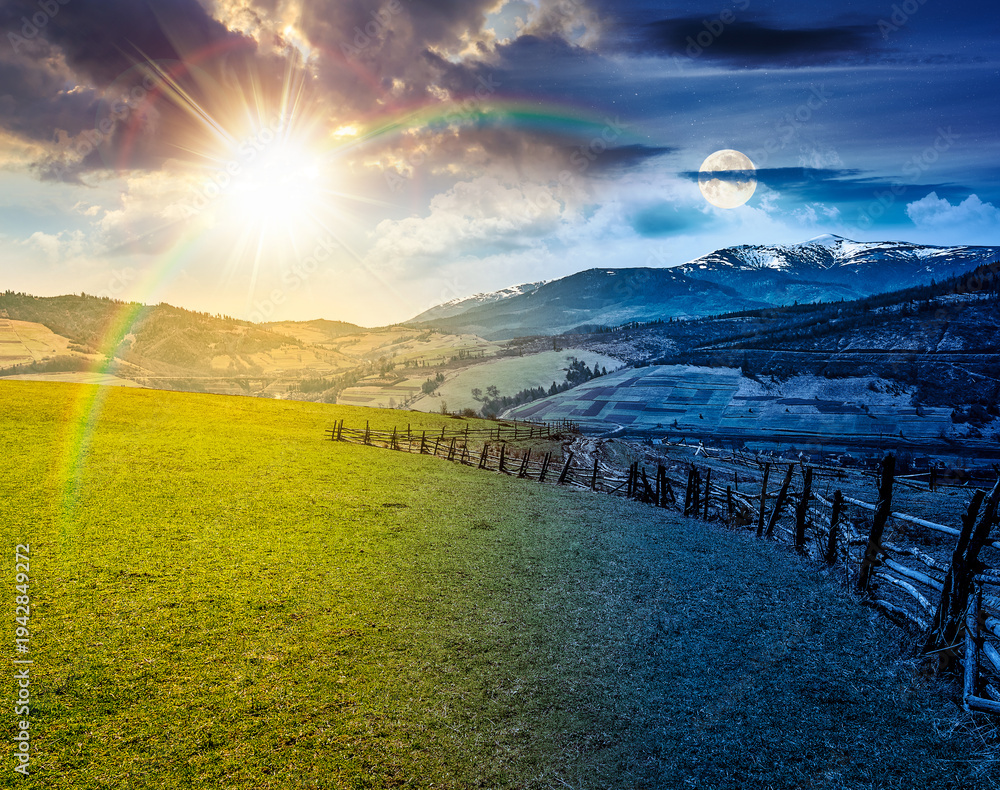 Obraz premium Spring equinox rural landscape. day meet night. sun and moon over Wooden fence along the path through agricultural fields in mountains. countryside scenery under cloudy sky. remote alpine pasture