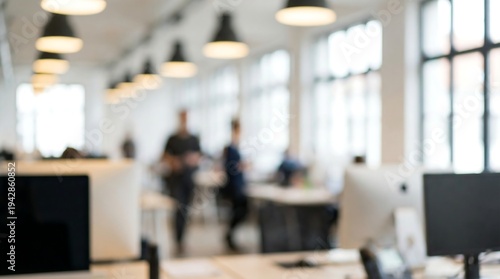 A blurred image of a bustling open-plan office shows modern desks, computers, and indistinct figures moving within the bright workspace.
