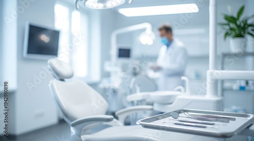 A modern dental office interior with a clean, white dental chair prominently in the foreground, while a blurred dentist works nearby.