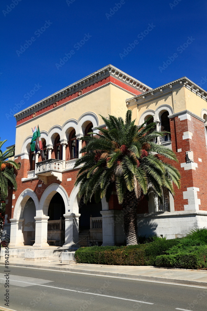 Obraz premium Historic Town Hall Building With Palm Trees And Flags On Mediterranean Facade, Croatia