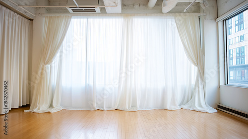 Empty studio room providing a minimalist backdrop with wooden floorboards and soft, diffused light from window white drapes