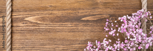 Rustic wooden banner with rope frame and pink flowers, wedding or Valentine greeting background