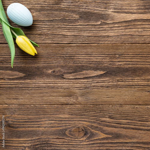 Square Easter eggs and spring flowers on rustic wooden table, social media post