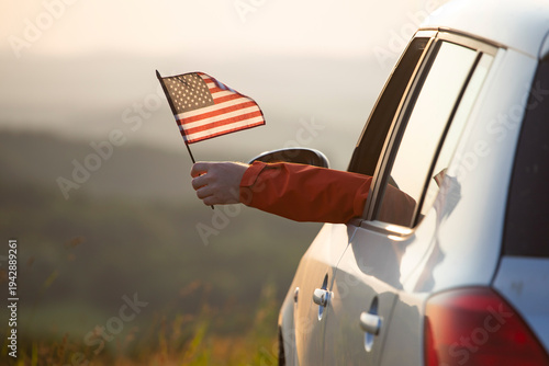Man in the car holding a waving american USA flag.