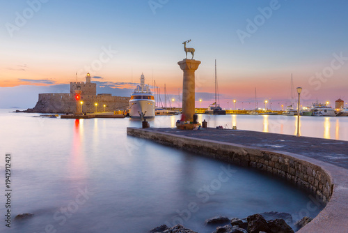 Mandraki harbor with deer statue at sunrise in Rhodes Greece