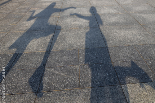 Two funny shadows of women facing each other on the square in the city. Walks of two girlfriends in the streets. Having fun, grimacing in the sun, making funny silhouettes