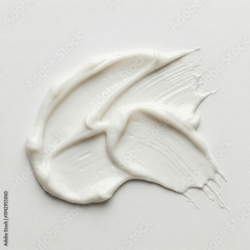 High-angle view of creamy white cosmetic texture stroke on white background