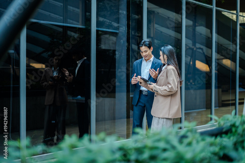Business colleagues businessman and woman sitting and discussing,planning work using tablet outside office.City meeting and laptop with business people outdoor urban and green area for collaboration