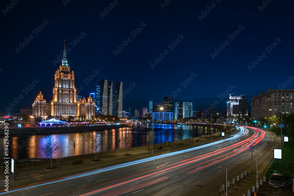 Obraz premium Night view of high-rise stalinist building and Moscow river with Moscow City buildings in the background in Moscow, Russia.