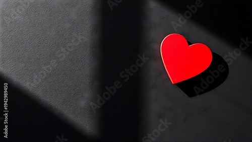 Red heart-shaped object on a dark textured surface, conveying emotion through minimalist design.