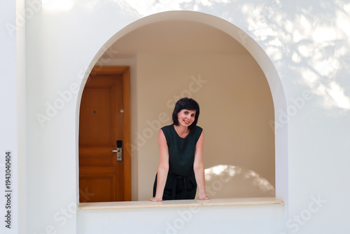 A woman looks out beautiful window opening.