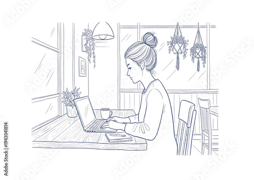 Young woman working on a laptop at a desk in a cozy cafe