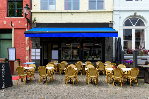 Old cozy street with tables of restaurant in Bruges (Brugge), West Flanders province, Belgium. Cityscape of Bruges.