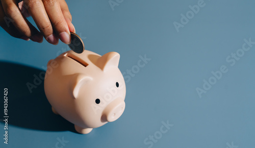 Konstfotografi Piggy bank coin hand saving finance money blue background close up personal fina