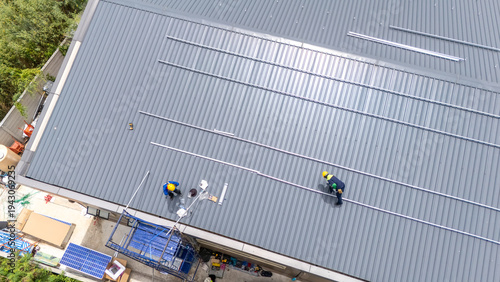Foto Workers installing solar panels on a metal roof, aerial view of renewable energy