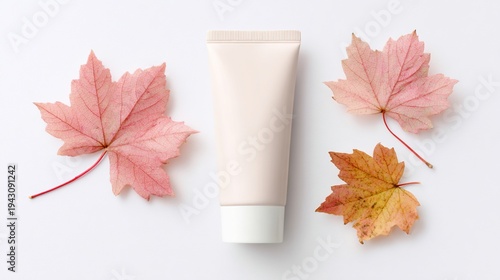 Cosmetic tube with autumnal leaves on a white background, suggesting skincare products