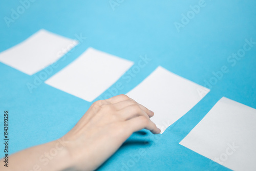 hand chooses from four blank white papers