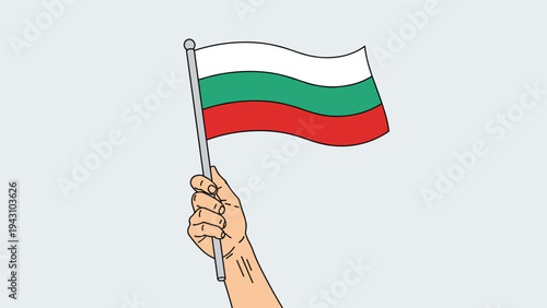 Hand holding a flag pole with the national flag of Bulgaria waving in the wind against a pale grey background.