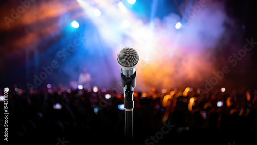 Microphone on stage with crowd and colorful lights in a concert setting, performing arts, music events, live shows, entertainment media promotion