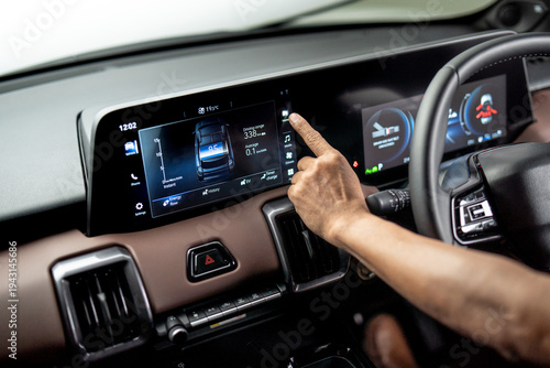 Obraz na plátně Hand operating infotainment touchscreen inside electric vehicle showing energy usage and driving range on digital dashboard display