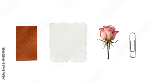A brown leather journal, a piece of white paper, a pink rose, and a paperclip on a white surface isolated on transparent background